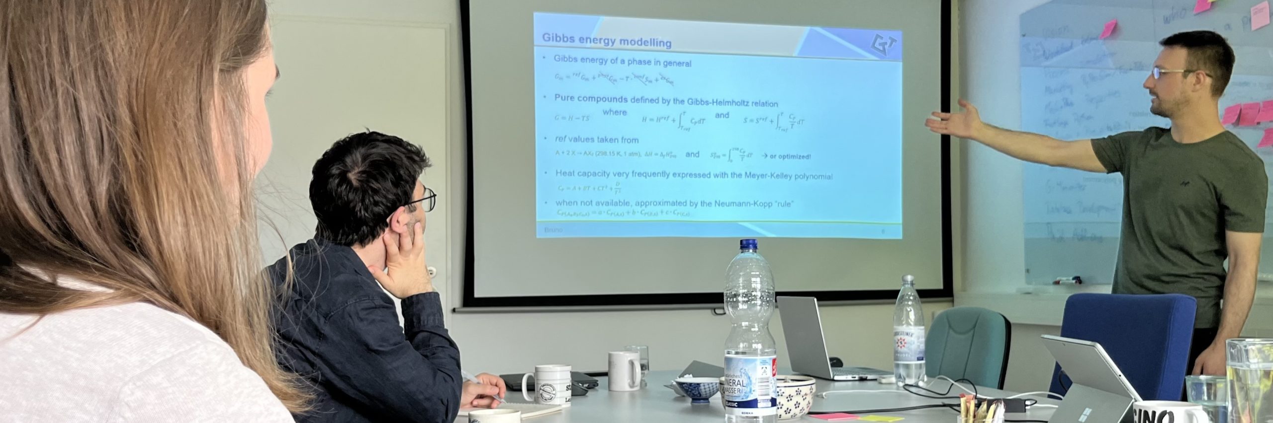 Team of thermodynamic enthusiasts collaborating during a meeting, featuring one person presenting while two others attentively watch.